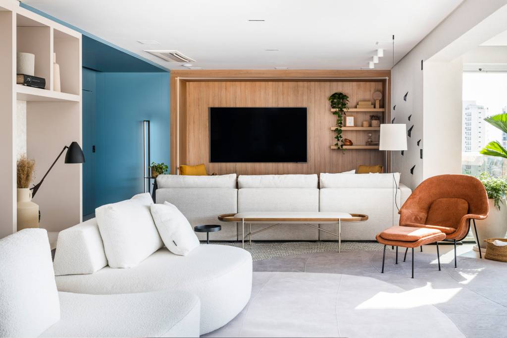 Apartamento pensado para receber com conforto tem toques de azul e mostarda. Projeto de Tetriz Arquitetura. Na foto, sala de estar, colorblocking azul, sofás brancos.