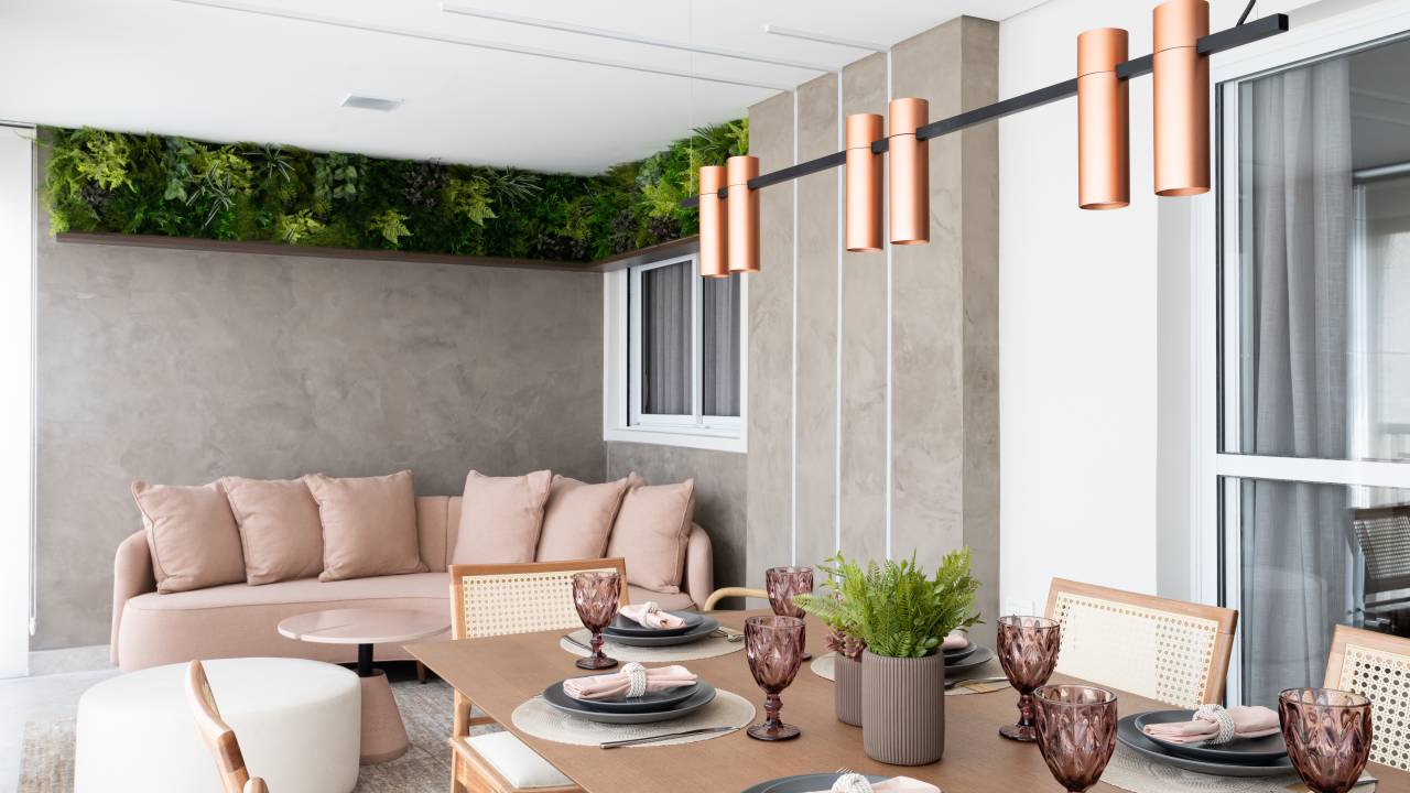 Apê de 240 m² mistura madeira, cimento queimado, metal e tons de preto, rosa e verde, do escritório Jessica Saka Interiores. Na foto, varanda com sofá rosa e plantas.
