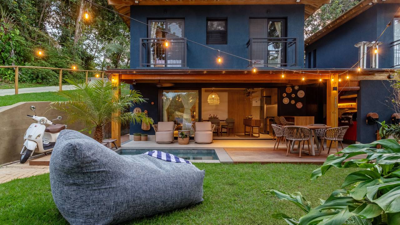 Casa de praia de 115 m² em meio à Mata Atlântica ganha linda fachada azul. Projeto de Juliana Zappa. Na foto, área externa, jardim, luzes.