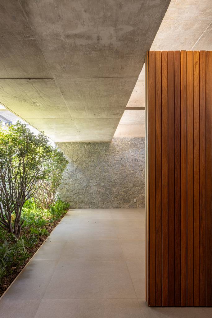 Concreto aparente marca estrutura de casa térrea com planta em formato L. Projeto de BLOCO Arquitetos.