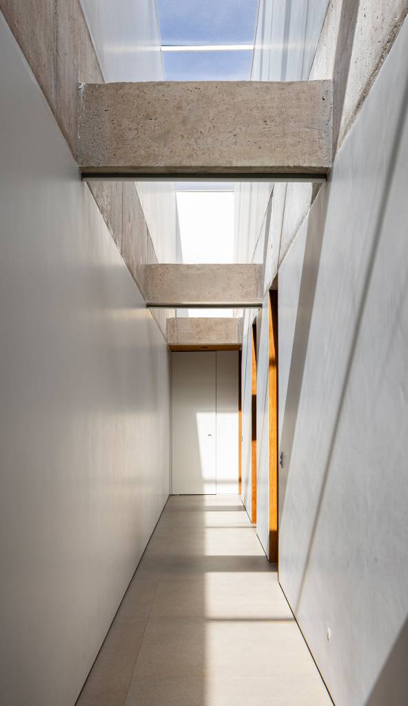 Concreto aparente marca estrutura de casa térrea com planta em formato L. Projeto de BLOCO Arquitetos.