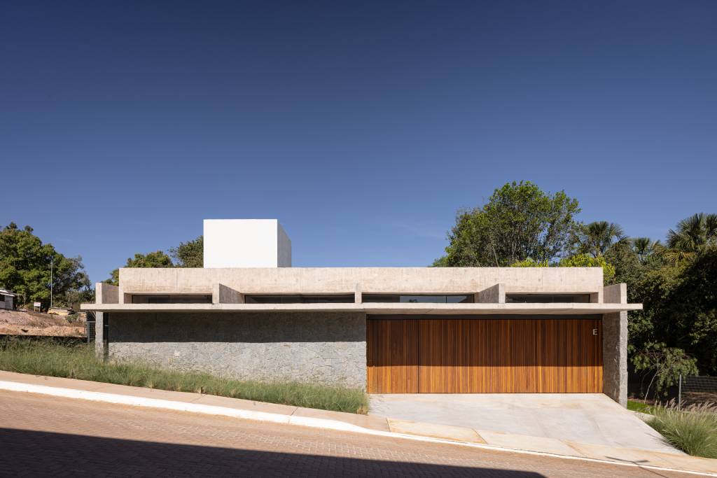 Concreto aparente marca estrutura de casa térrea com planta em formato L. Projeto de BLOCO Arquitetos.