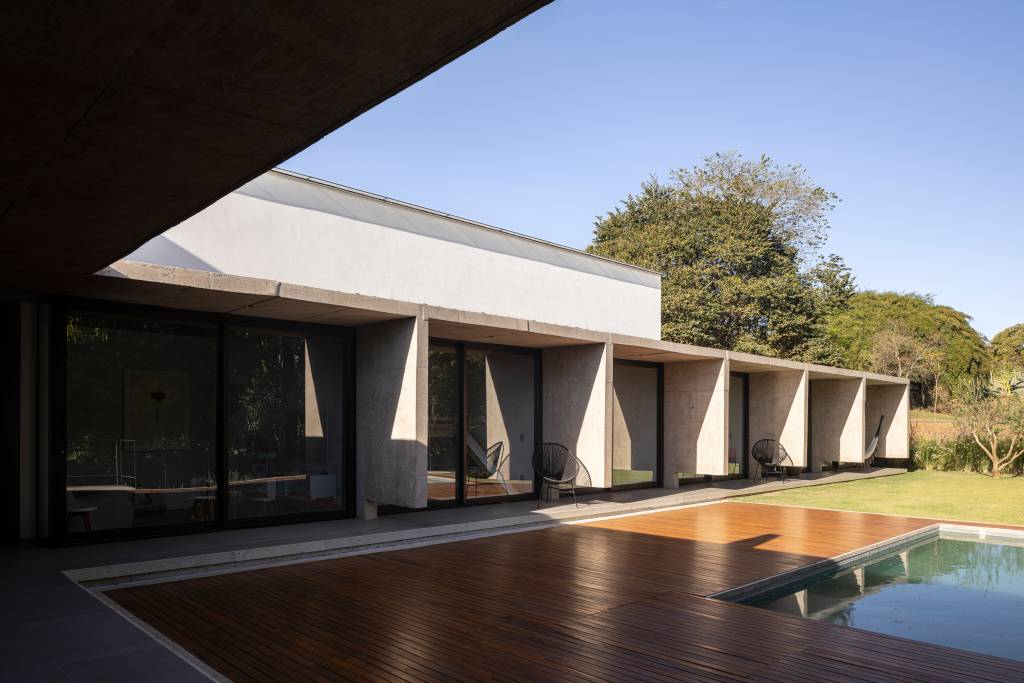 Concreto aparente marca estrutura de casa térrea com planta em formato L. Projeto de BLOCO Arquitetos.