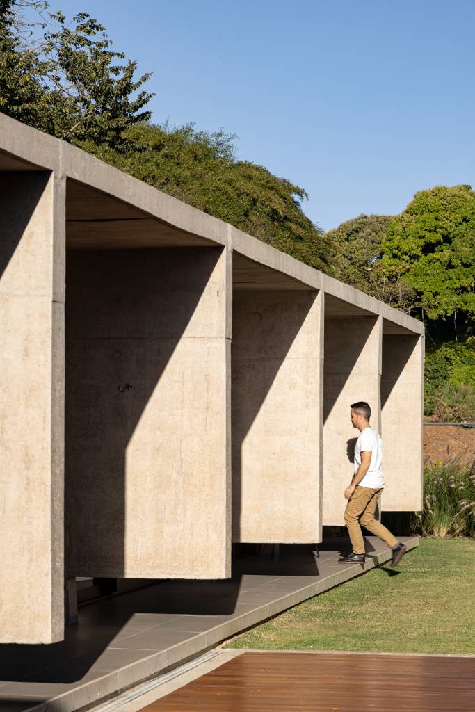 Concreto aparente marca estrutura de casa térrea com planta em formato L. Projeto de BLOCO Arquitetos.