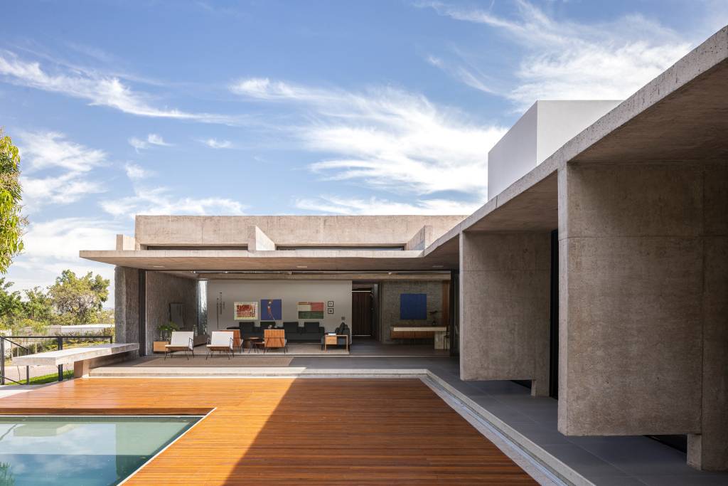 Concreto aparente marca estrutura de casa térrea com planta em formato L. Projeto de BLOCO Arquitetos.