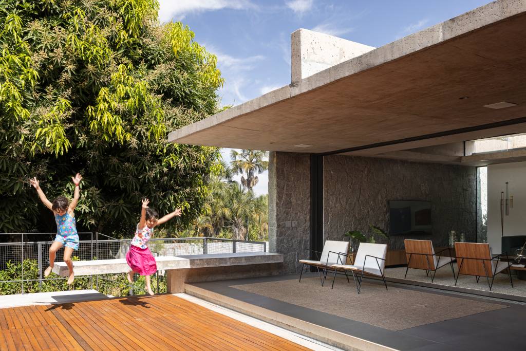 Concreto aparente marca estrutura de casa térrea com planta em formato L. Projeto de BLOCO Arquitetos.