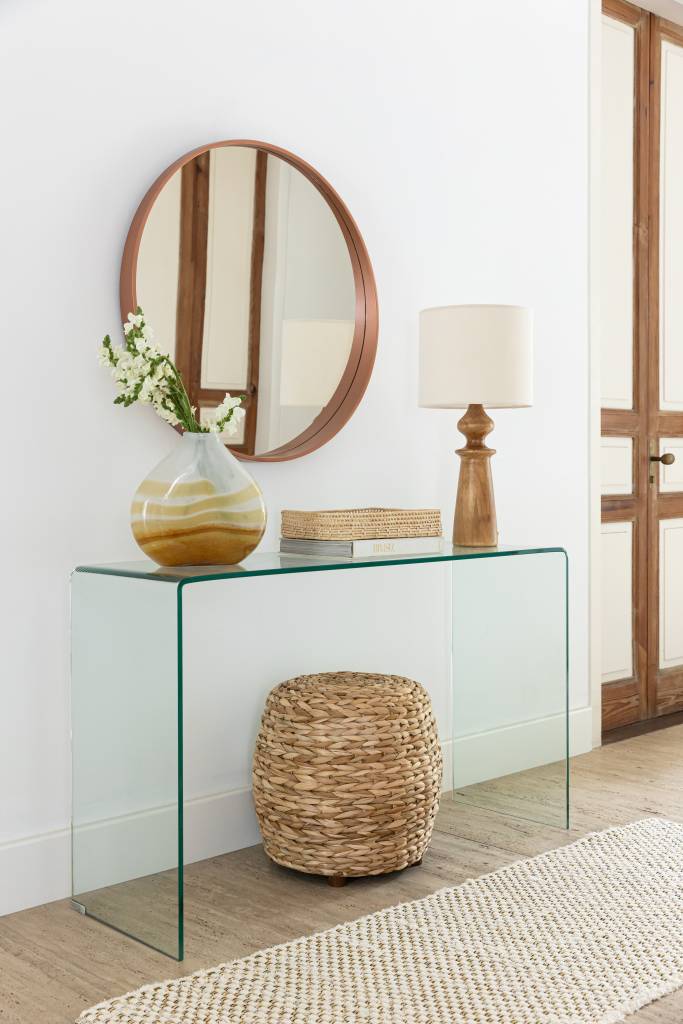 5 dicas exclusivas para decorar apartamentos pequenos. Na foto, hall de entrada, espelho redondo, aparador de vidro.