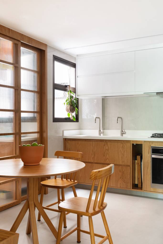 Madeira e palhinha marcam presença nos móveis e marcenaria de apê de 100 m². Projeto de Co+Lab Juntos Arquitetura. Na foto, copa de cozinha, canto alemão.