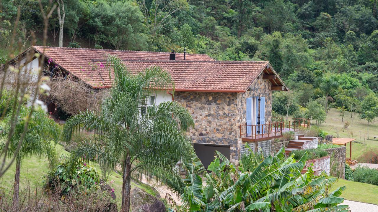 Paredes de pedra e lareira dão charme à casa de campo sustentável. Projeto de Falchi Arquitetura.