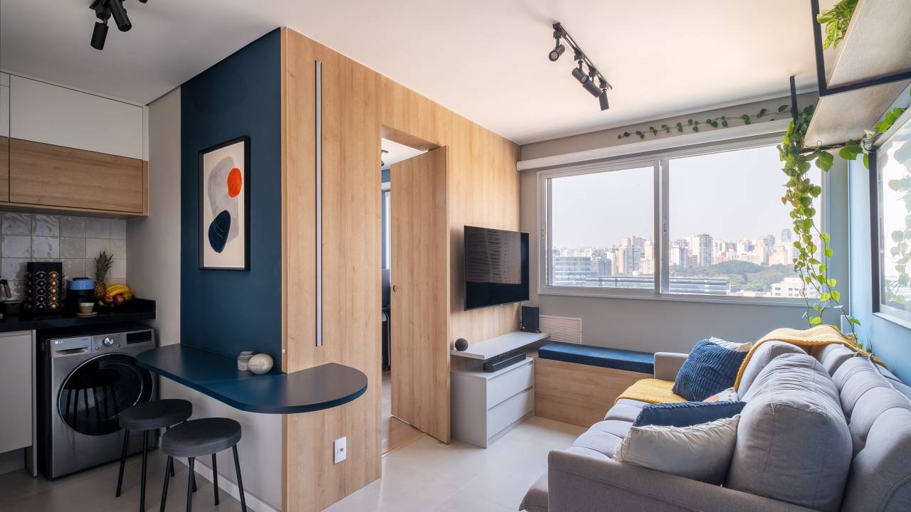 Projeto de iluminação ressalta o azul neste apartamento de 34 m². Projeto Dua Arquitetura e Bya Ribeiro. Na foto, sala integrada, bancada curva.