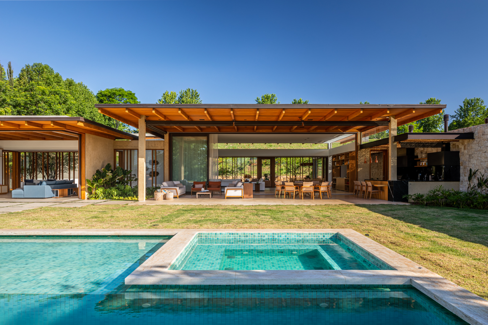 Vidro e brises de madeira conectam casa com 7 suítes com a natureza. Projeto de Gilda Meirelles Arquitetura.