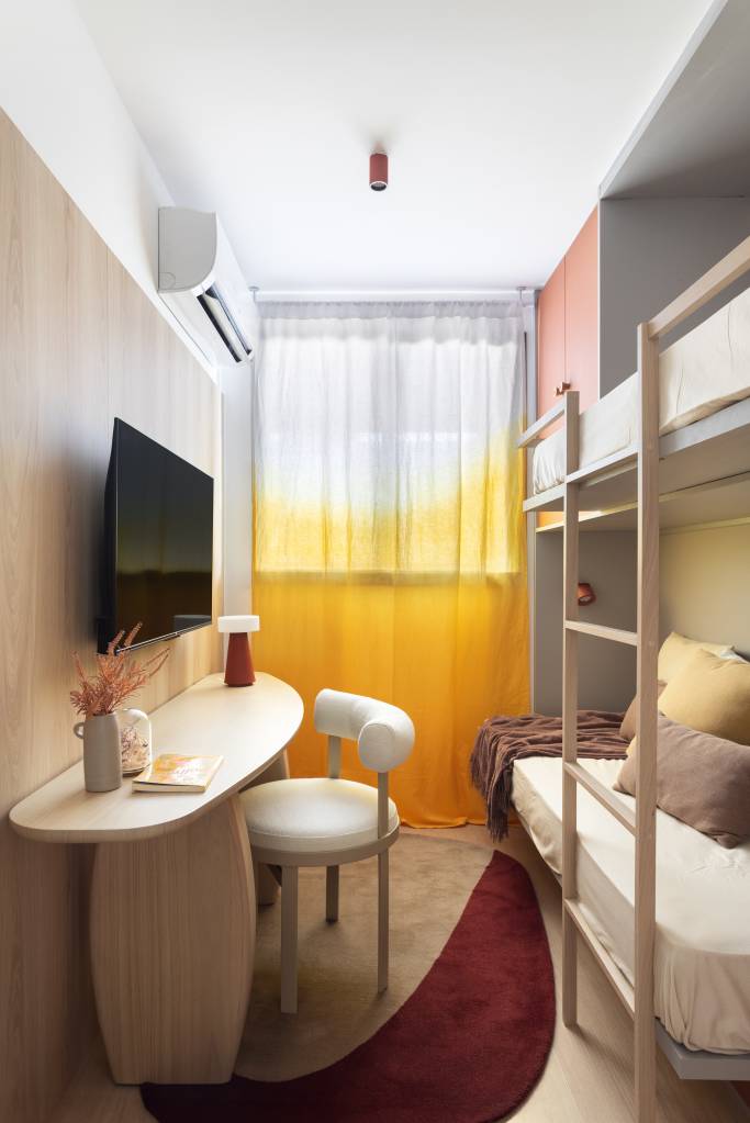 Apê neutro e compacto de 55 m² tem uma suíte e revestimento cerâmico na sala. Projeto de Studio Leandro Neves. Na foto, quarto infantil, beliche, cortina colorida.