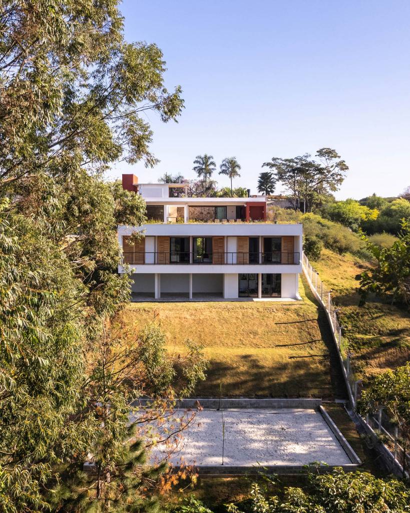 Casa de condomínio ganha salão de jogos, estúdio de música e quadra de areia. Projeto de Carolina Penna Arquitetos.