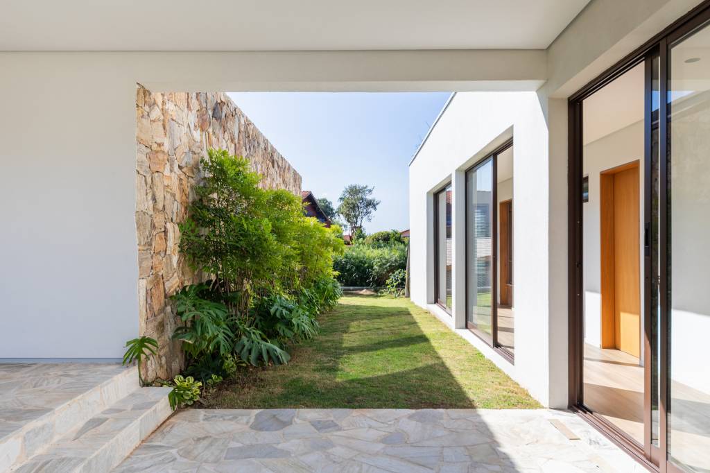 Casa de condomínio ganha salão de jogos, estúdio de música e quadra de areia. Projeto de Carolina Penna Arquitetos.