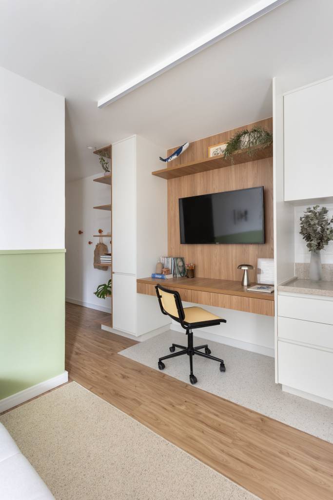 Estúdio de 40 m² se destaca pelo estilo aesthetic e cabeceira de MDF verde. Projeto de Rawi Arquitetura + Design. Na foto, home office pequeno.