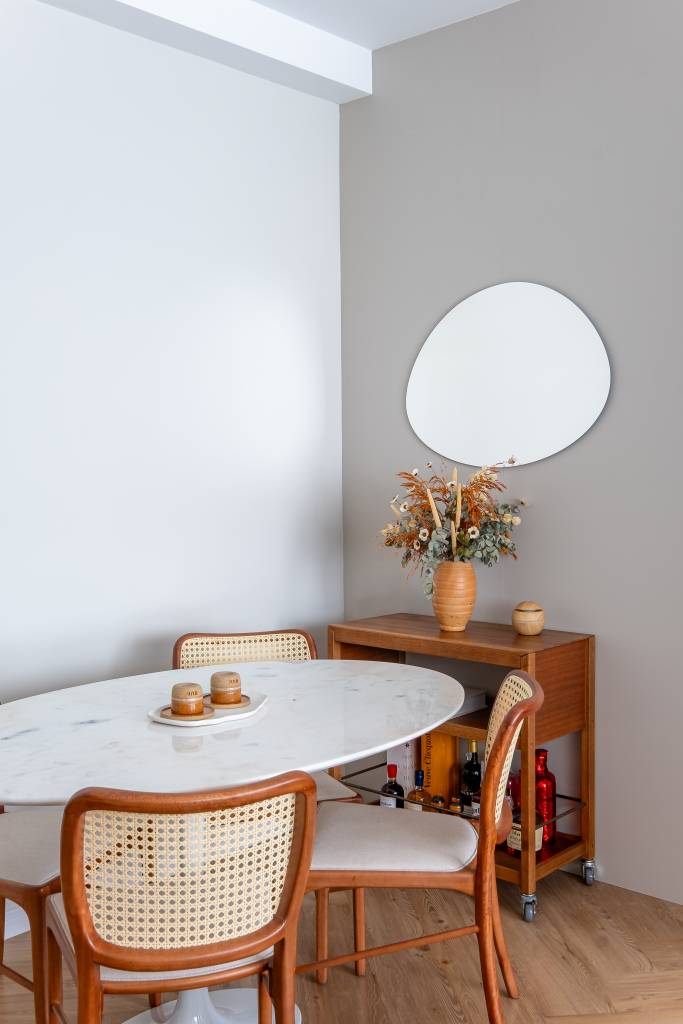 Marcenaria planejada é rack na sala e guarda-roupa no quarto neste apê de 39 m². Projeto de Bya Ribeiro Arquitetura e Thaís Viana. Na foto, sala de jantar, espelho, mesa oval.
