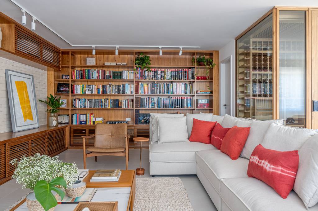 Minimalismo japonês inspira decoração de cobertura com 293 m². Projeto de Carmen Zaccaro. Na foto, sala, sofá cinza, estante com livros.