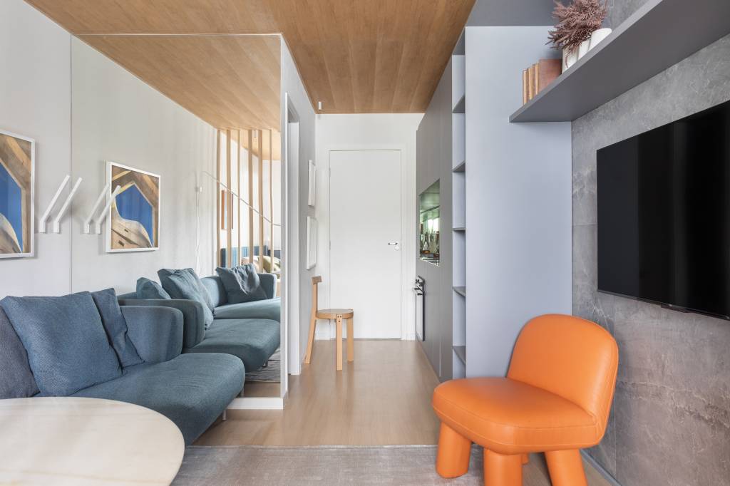 Parede lateral do sofá e backsplash da cozinha de apê ganham espelhos para amplitude