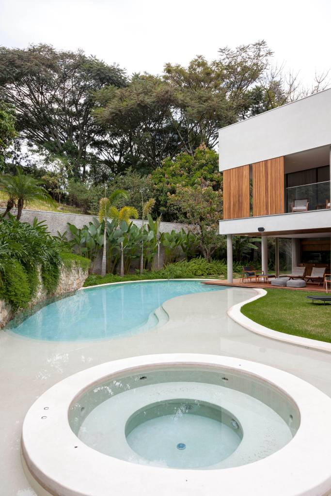 Piscina em forma de lago e suíte de 150 m² são destaque em casa. Projeto de DB Arquitetos.