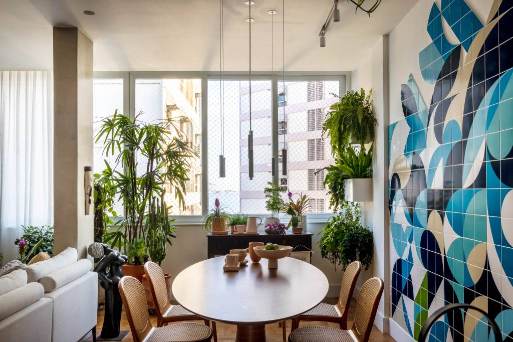 Plantas, azulejos e detalhes com temas marinhos dão charme à apê de 100 ². Projeto de Paula Neder. Na foto, sala, mesa oval, plantas.