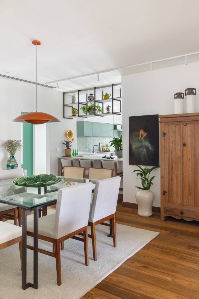Reforma cria cristaleira na marcenaria em cozinha de apartamento de 180 m². Projeto de Vivian Reimers. Na foto, sala de jantar, mesa com tampo de vidro, cadeiras.