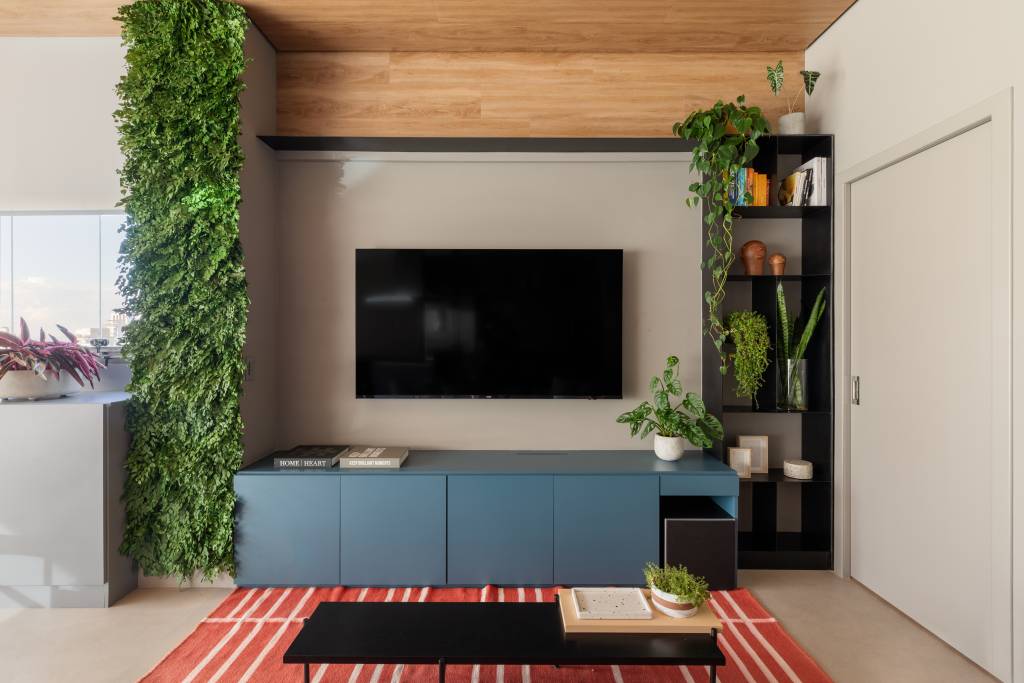 Ape-de-100-m2-com-pe-direto-de-3-m-ganha-solucoes-criativas-Michelle-Machado-jardim-vertical-08 Apê de 100 m² com pé-direto de 3 m ganha soluções criativas. Projeto de Michelle Machado. Na foto, sala com TV e armário azul.