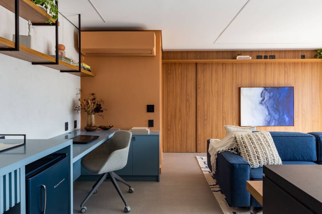 Ar-condicionado colorido? Saiba como incluir o equipamento na decoração. Projeto de Mari Milani Arquitetura. Na foto, sala com parede e ar-condicionado amarelo.