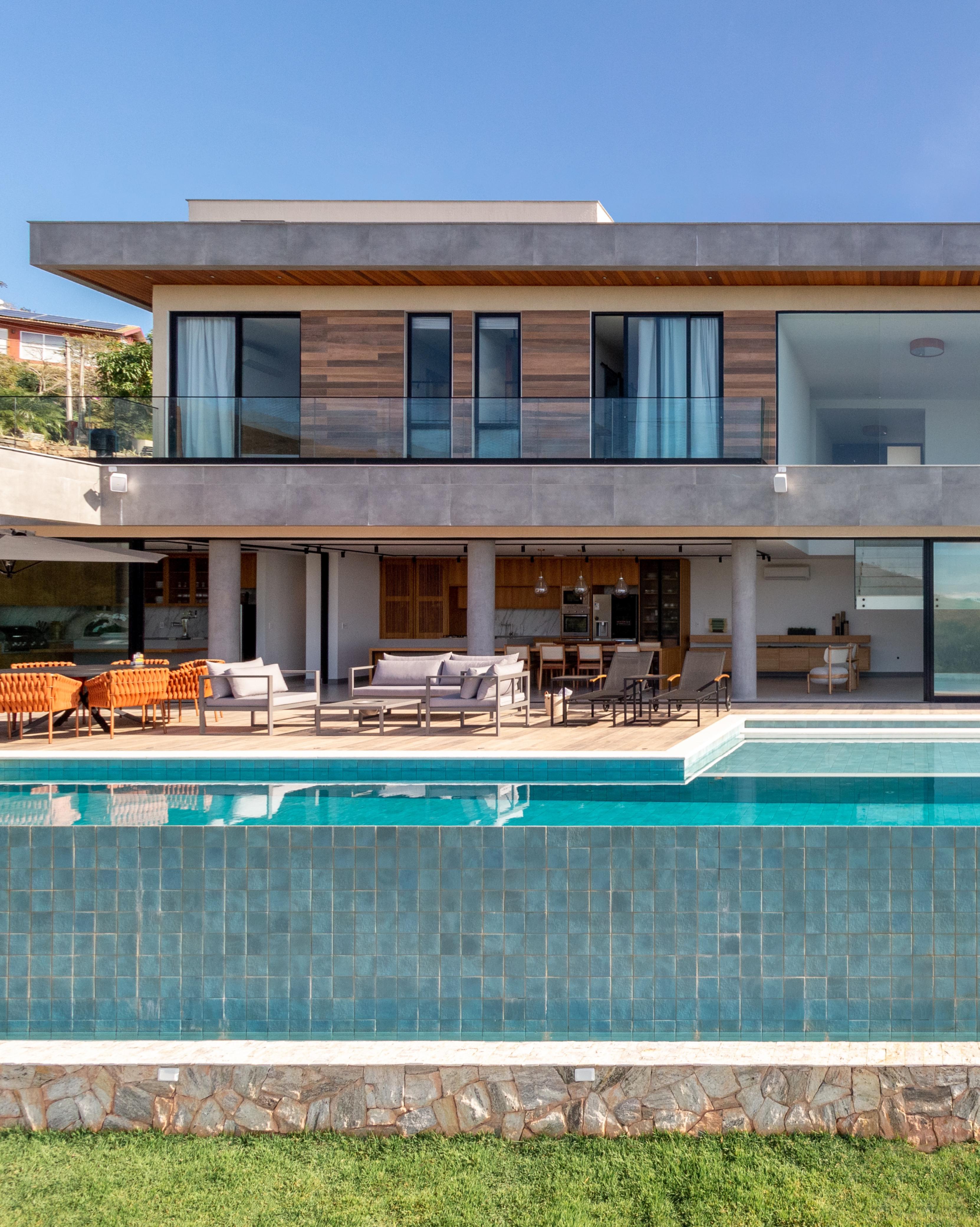 Casa de 720 m² fica no topo de uma montanha no RJ. Projeto de Rafael Ramos. Na foto, área externa da casa, com piscina e espaço gourmet.