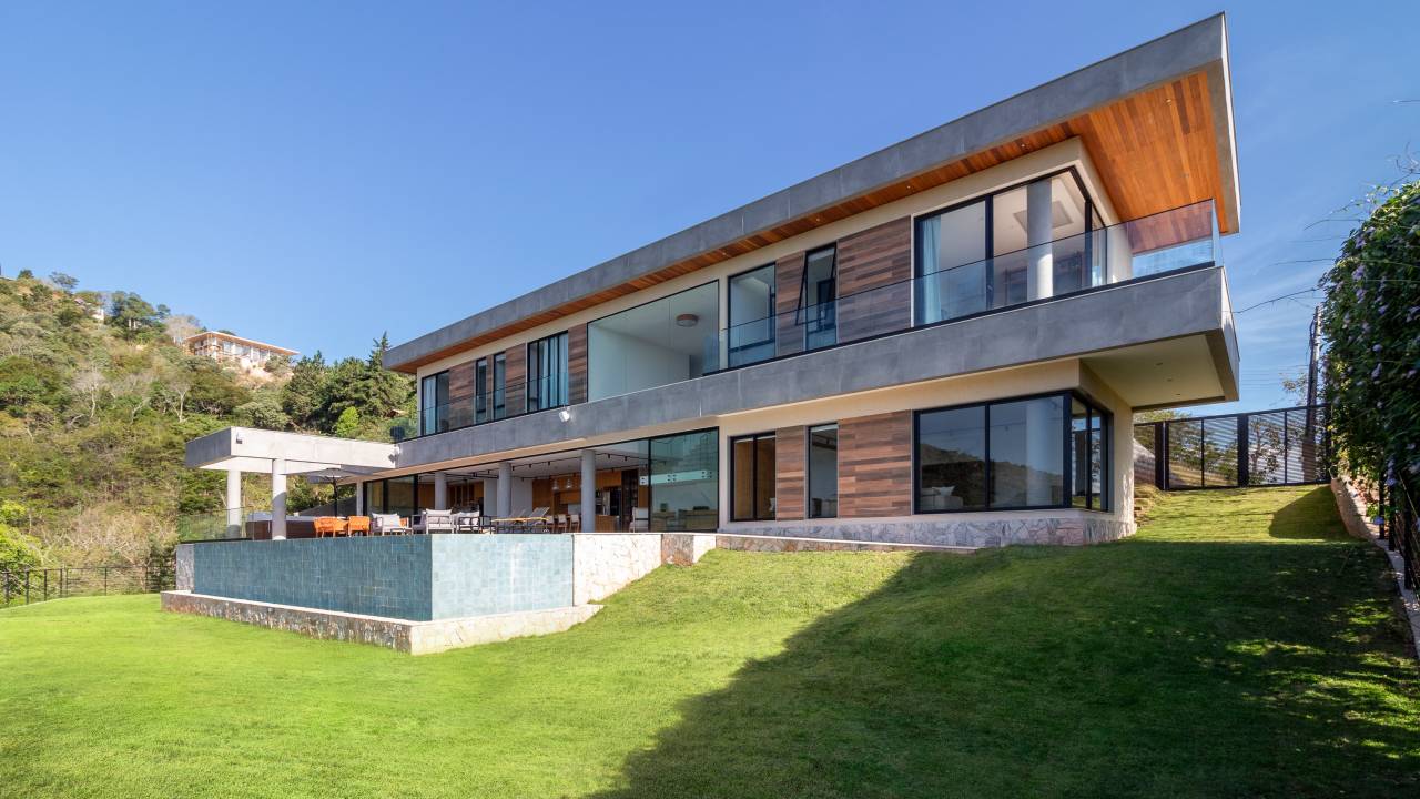 Casa de 720 m² fica no topo de uma montanha no RJ. Projeto de Rafael Ramos. Na foto, área externa da casa, com piscina e espaço gourmet.