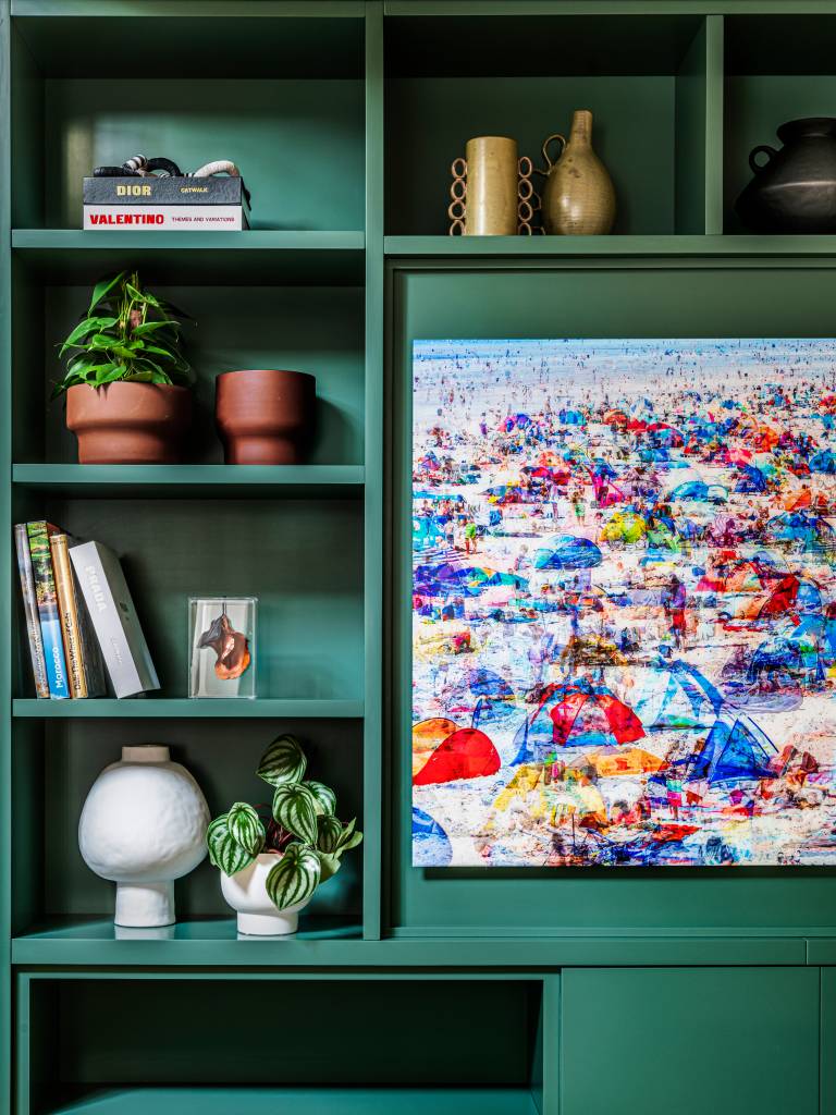 Painel e forro de madeira esconde a área íntima deste apê de 297 m², projeto de Vivi Cirello. Na foto, móvel verde com plantas, objetos decorativos e livros