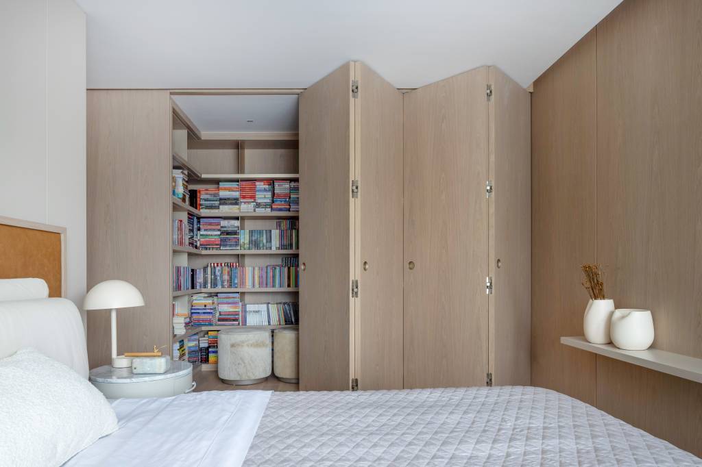 Biblioteca, cores neutras e materiais naturais criam apê refúgio para leitura. Estúdio Elmor. Quarto e biblioteca com porta camarão.