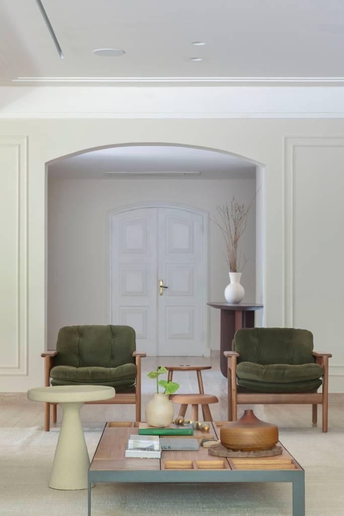 Casa em estilo clássico europeu tem piso mármore e árvore na área gourmet. Projeto de Studio LAK. Na foto, sala de estar, poltronas verdes, boiseries.