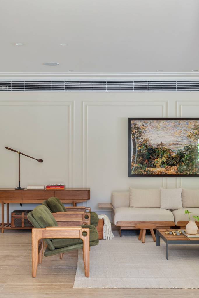 Casa em estilo clássico europeu tem piso mármore e árvore na área gourmet. Projeto de Studio LAK. Na foto, sala de estar, boiseries, sofá branco, poltronas verdes.