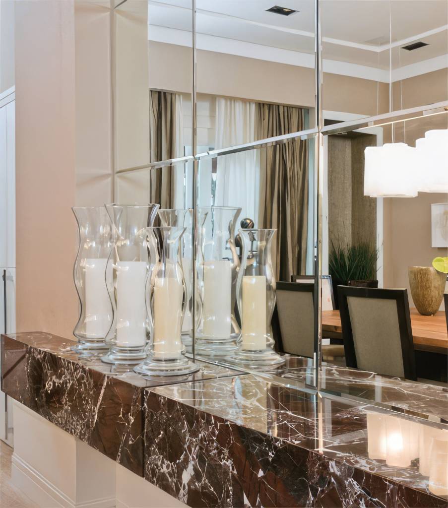Imagem de um interior moderno e elegante, onde os espelhos são estrategicamente posicionados para refletir a luz natural, ampliando a sensação de espaço. Os espelhos são de diferentes formatos e tamanhos, integrados à decoração, proporcionando um efeito visual interessante e sofisticado.