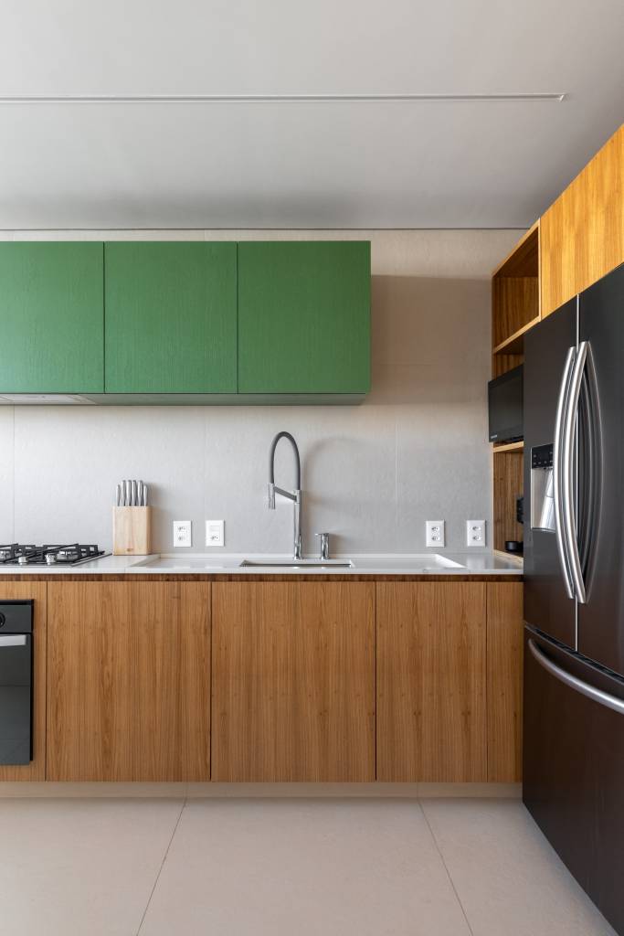 Forro de madeira e painel de mármore são destaques em área social de apartamento. Cozinha.