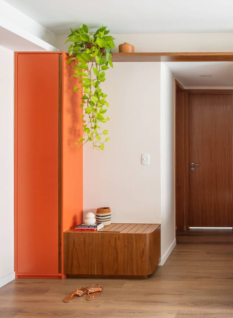 Renovação econômica deixa apê de 70 m² mais colorido com laranja e verde. Projeto Co+Lab Juntos Arquitetura. Na foto, hall de entrada, banco, planta suspensa.