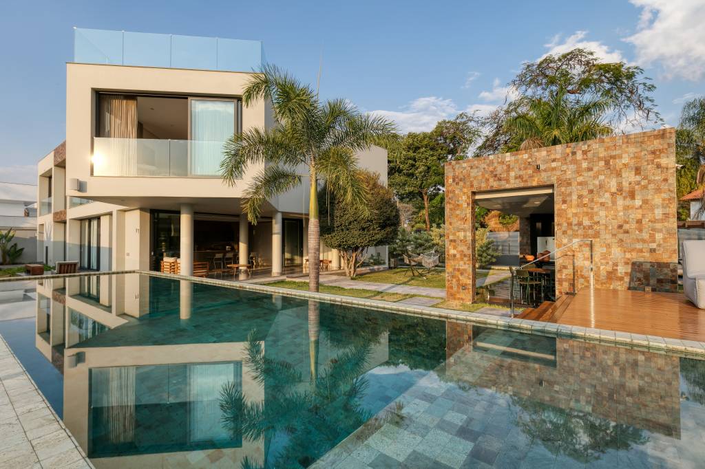 Tons neutros e grandes aberturas valorizam a vista de casa na Pampulha. Externa com piscina.