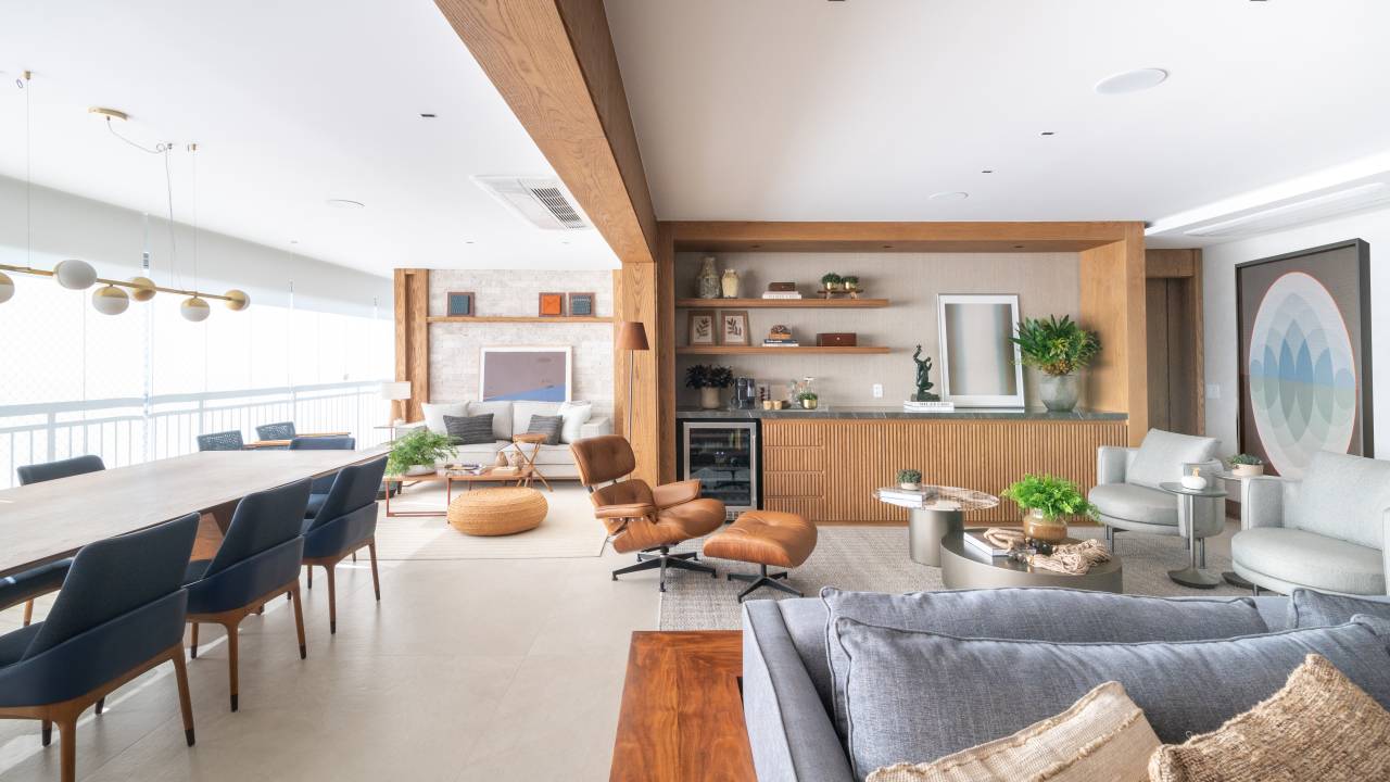 Varanda gourmet com churrasqueira a gás é destaque em apartamento. Projeto de Andrea Teixeira. Na foto, ambiente integrado, poltrona, pórtico de madeira.