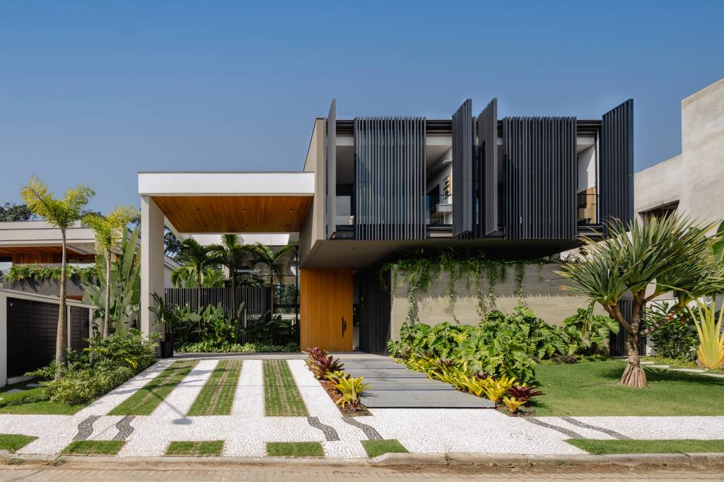 Casa-possui-areas-sociais-envolvidas-por-vidro-e-vista-para-a-Mata-Atlantica-Raiz-Arquitetura-09 Casa possui áreas sociais envolvidas por vidro e vista para a Mata Atlântica. Projeto de Raiz Arquitetura. Na foto, fachada de casa com painel de brises.