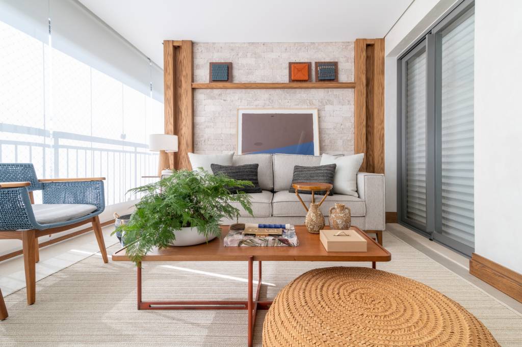 Cinco formas de explorar o pé-direito em uma residência. Projeto de Andrea Teixeira Arquitetura e Interiores. Na foto, varanda com sofá e mesa de centro.
