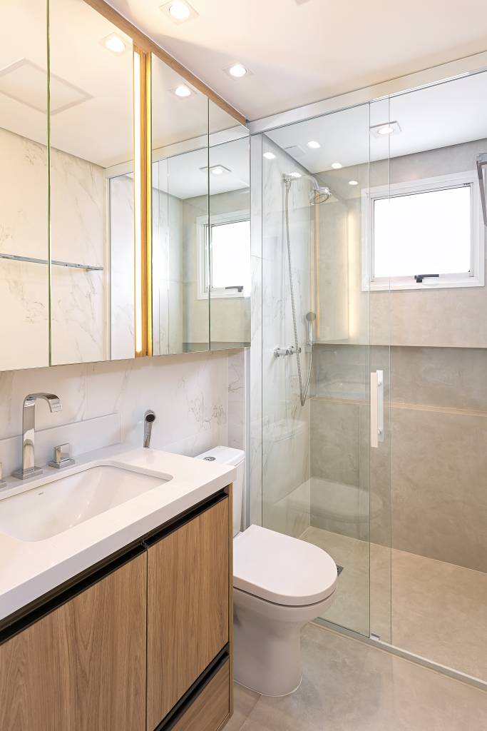 Neste apartamento de 103 m², cristaleira multifuncional também é adega. Projeto de RMV Interiores. Na foto, banheiro, armário aéreo espelhado.