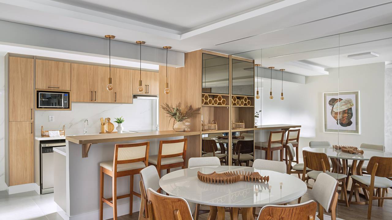 Neste apartamento de 103 m², cristaleira multifuncional também é adega. Projeto de RMV Interiores. Na foto, cozinha integrada, mesa redonda.