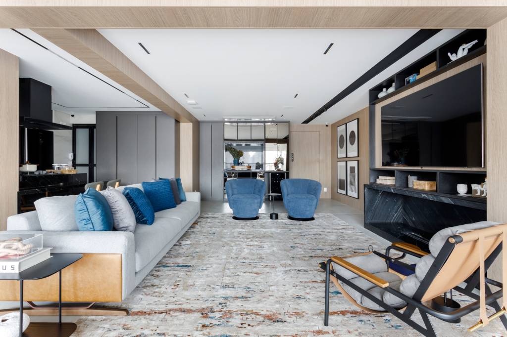 Apê de 147 m² tem dois escritórios — um deles na varanda! Projeto de Aline Lopes. Living com poltronas e almofadas azuis.