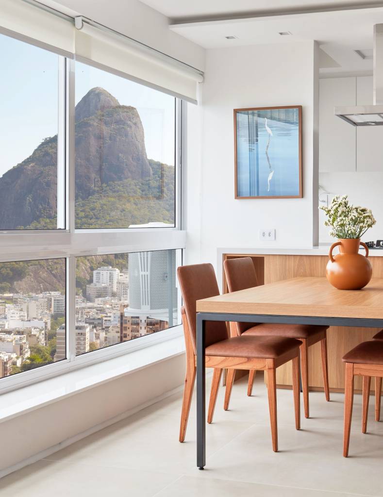 Apê de 50 m² tem portas de correr e bancada de trabalho na estante. Projeto de Carolina Gouvea Arquitetura. Na foto, sala de jantar, grandes janelas.