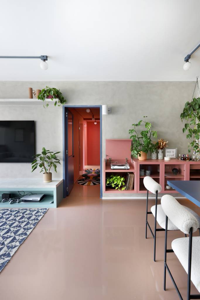 Apê tem paleta com 30 cores alegres e aparador com floreira. Projeto de Studio 92 Arquitetura. Na foto, sala, aparador rosa, corredor com colorblock rosa.