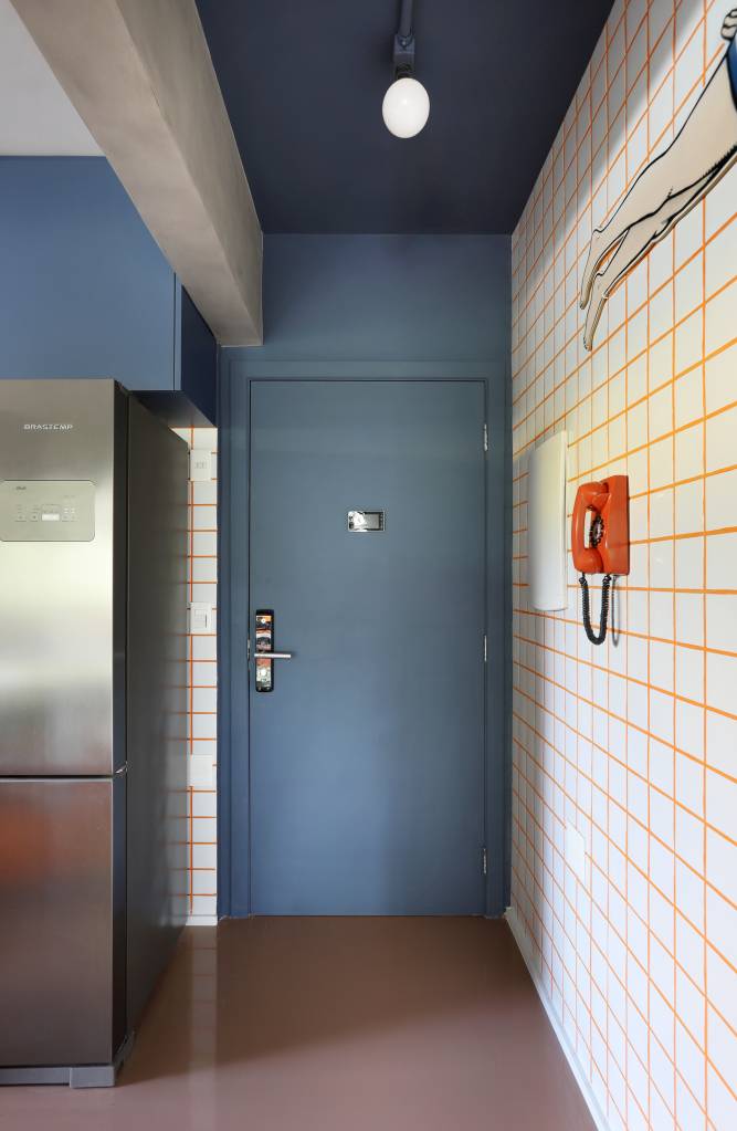 Apê tem paleta com 30 cores alegres e aparador com floreira. Projeto de Studio 92 Arquitetura. Na foto, entrada, porta azul.