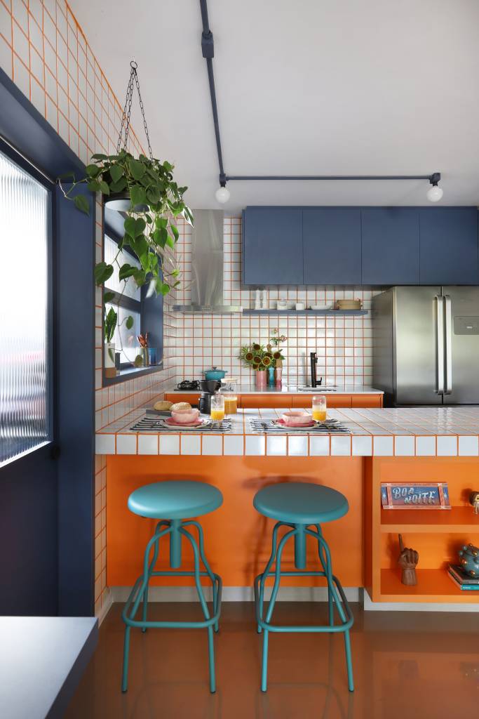 Apê tem paleta com 30 cores alegres e aparador com floreira. Projeto de Studio 92 Arquitetura. Na foto, cozinha azul e laranja com azulejos.
