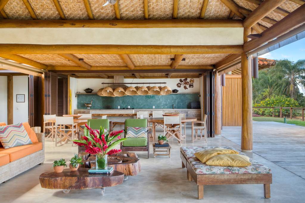 Linda casa de campo tem estrutura de eucalipto e décor rústico chic. Projeto de Solange Calio. Na foto, sala de estar, área gourmet integrada com área externa.