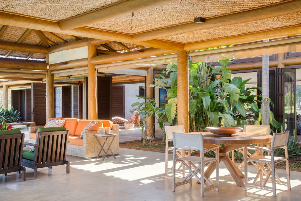 Linda casa de campo tem estrutura de eucalipto e décor rústico chic. Projeto de Solange Calio. Na foto, área social integrada com área externa.