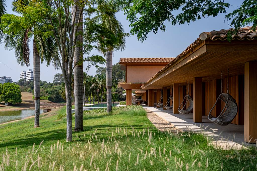 Casa de campo tem piscina semiolímpica e oito suítes elegantes. Projeto de Studio DWG. Na foto, varanda coberta, cadeira de balanço.